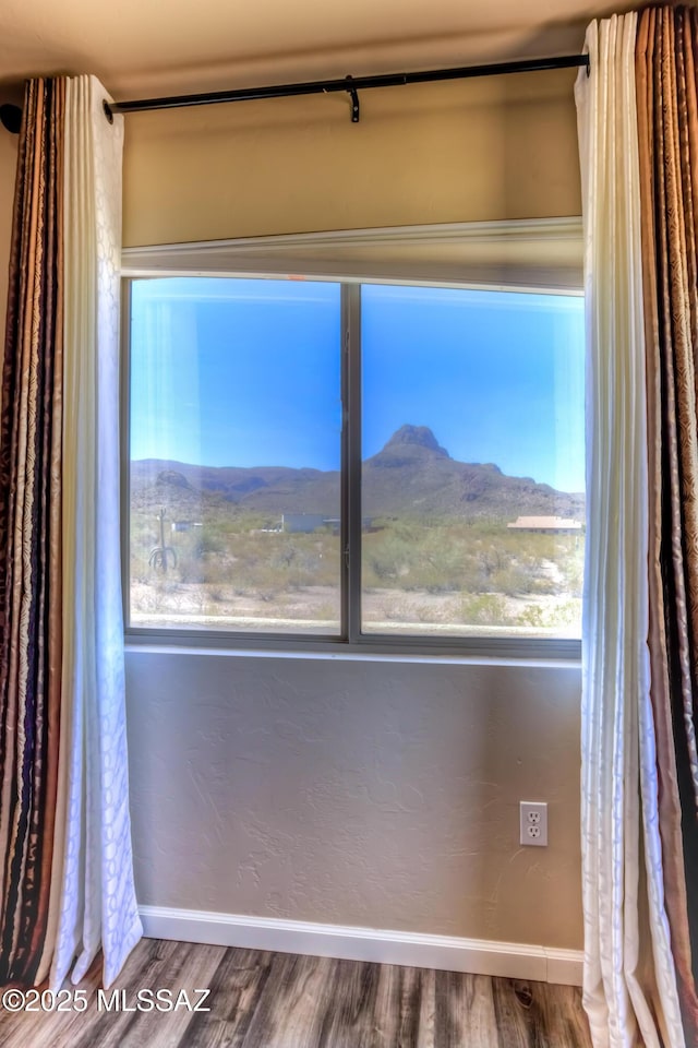 empty room with a mountain view, wood finished floors, and baseboards