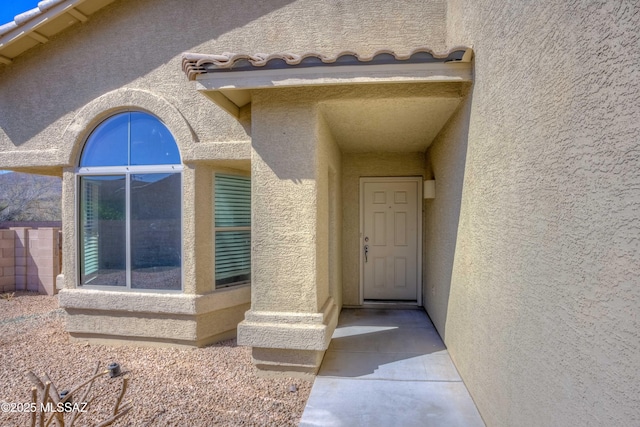 property entrance featuring a tiled roof and stucco siding