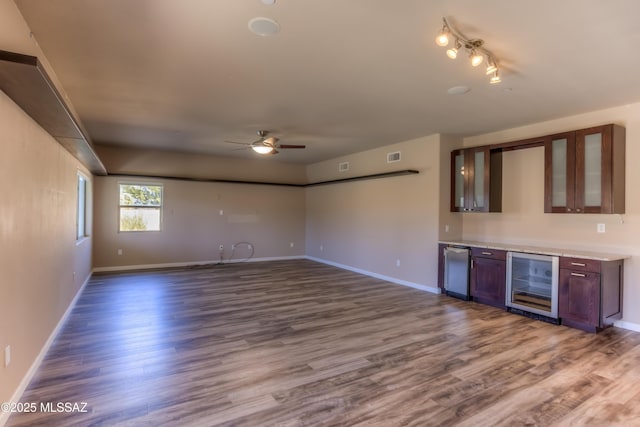 interior space with wine cooler, wood finished floors, baseboards, and ceiling fan