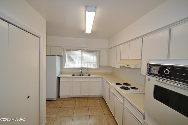 kitchen with under cabinet range hood, white appliances, a sink, white cabinets, and light countertops