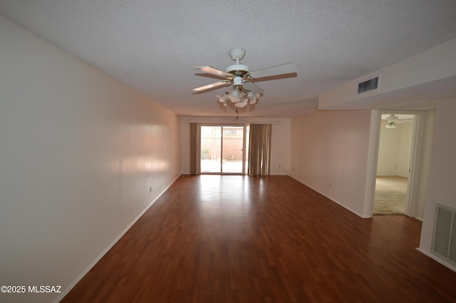 empty room with a textured ceiling, visible vents, a ceiling fan, and wood finished floors