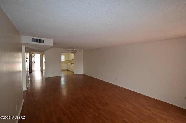 unfurnished room featuring a textured ceiling, visible vents, and wood finished floors