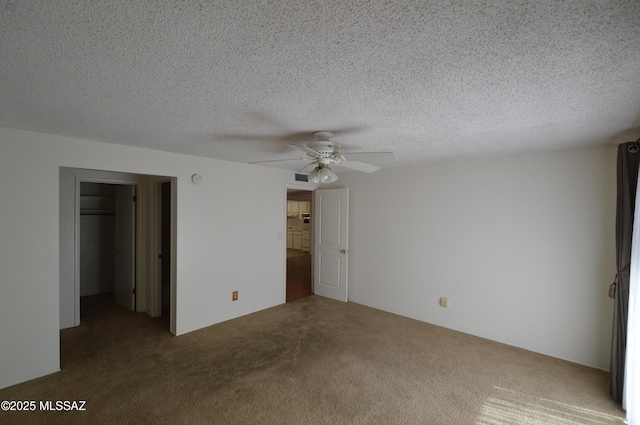 unfurnished bedroom featuring ceiling fan, a spacious closet, a textured ceiling, carpet flooring, and a closet