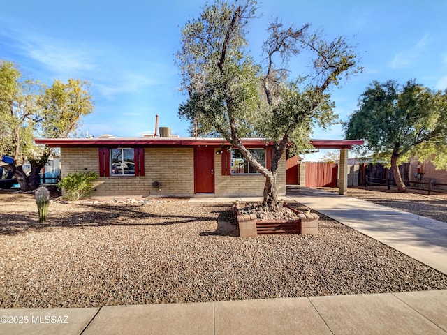 ranch-style house with driveway, fence, a carport, and brick siding