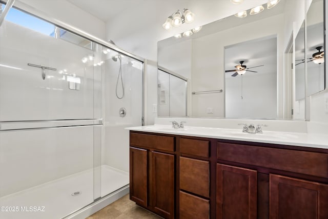 bathroom featuring a ceiling fan, a shower stall, double vanity, and a sink