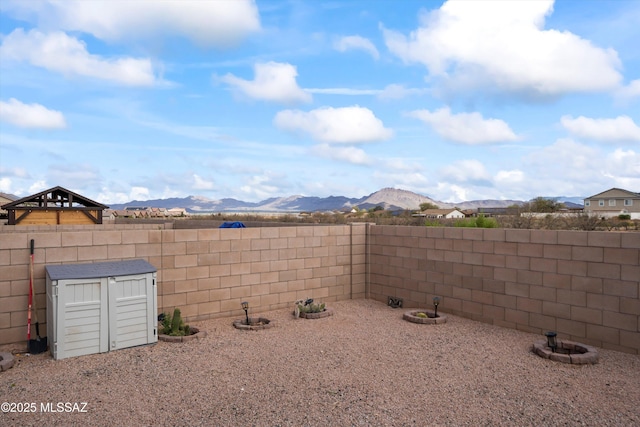 view of yard with a storage unit, a mountain view, an outbuilding, and a fenced backyard