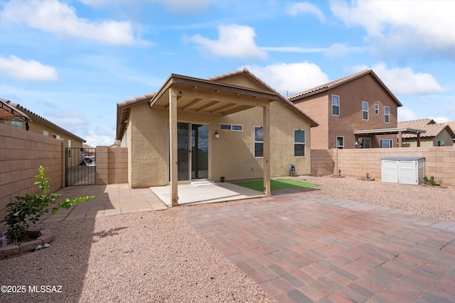 rear view of house featuring a patio, a gate, a fenced backyard, stucco siding, and a tile roof