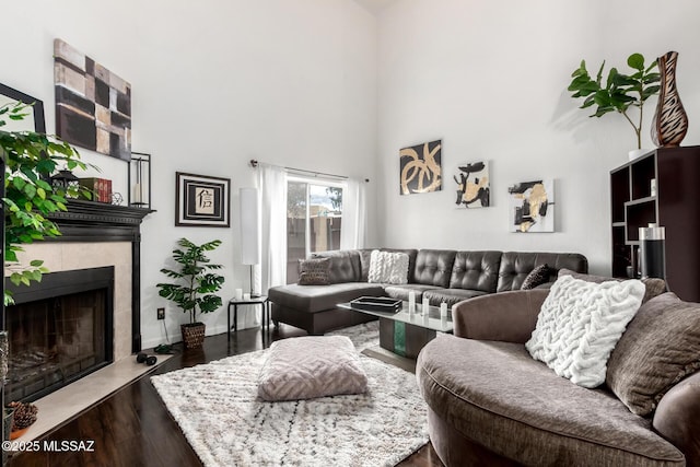 living area featuring dark wood finished floors, a fireplace, and a towering ceiling