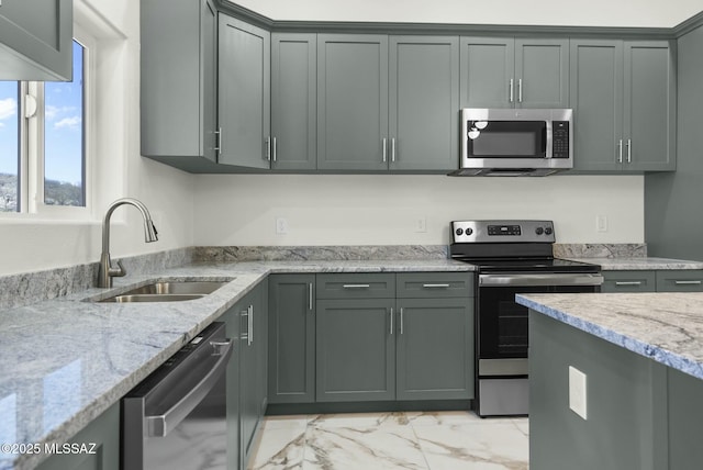 kitchen featuring marble finish floor, appliances with stainless steel finishes, a sink, and light stone counters