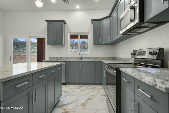 kitchen with recessed lighting, a sink, marble finish floor, appliances with stainless steel finishes, and light stone countertops