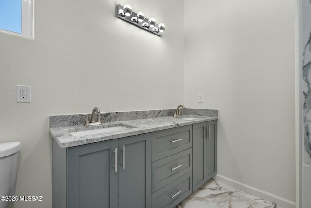 bathroom with marble finish floor, a sink, toilet, and baseboards