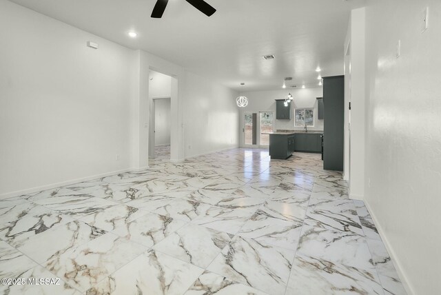 unfurnished living room featuring a ceiling fan, baseboards, visible vents, and a sink