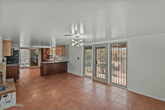 kitchen with visible vents, a chandelier, a peninsula, dark countertops, and tile patterned flooring