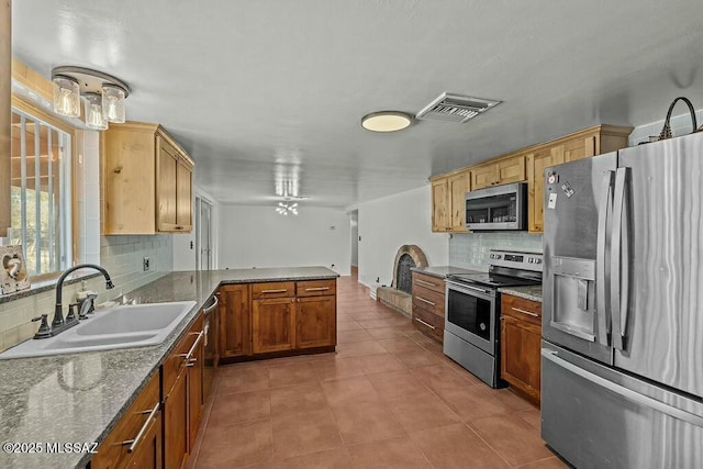 kitchen with light tile patterned floors, a sink, visible vents, a peninsula, and appliances with stainless steel finishes
