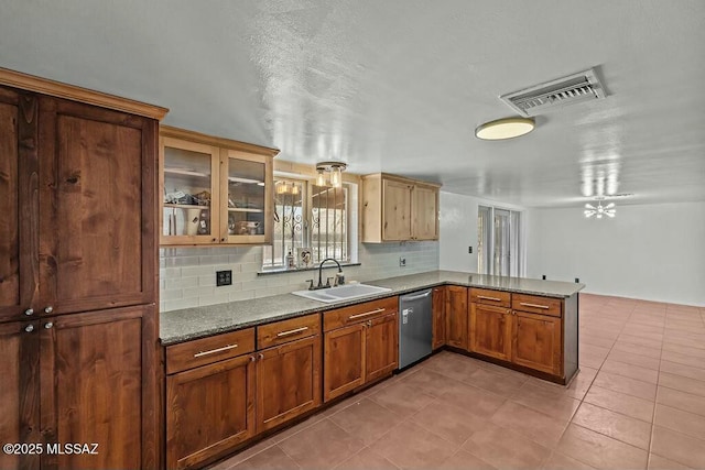 kitchen featuring backsplash, a sink, visible vents, dishwasher, and a peninsula