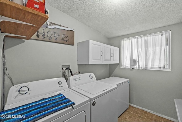 laundry room with baseboards, washing machine and clothes dryer, cabinet space, and a textured ceiling