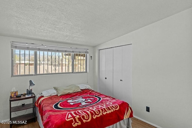 bedroom featuring a textured ceiling, a closet, vaulted ceiling, and wood finished floors
