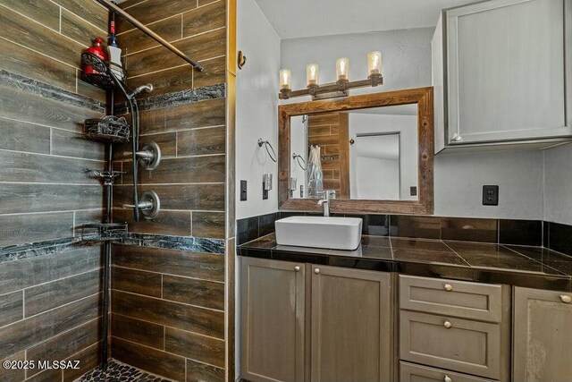 full bathroom with a tile shower and vanity