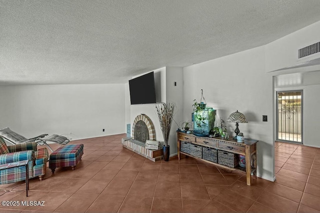tiled living room featuring a textured ceiling, a fireplace, and visible vents