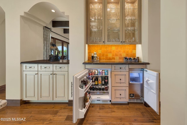 bar with a bar, hardwood / wood-style floors, and decorative backsplash