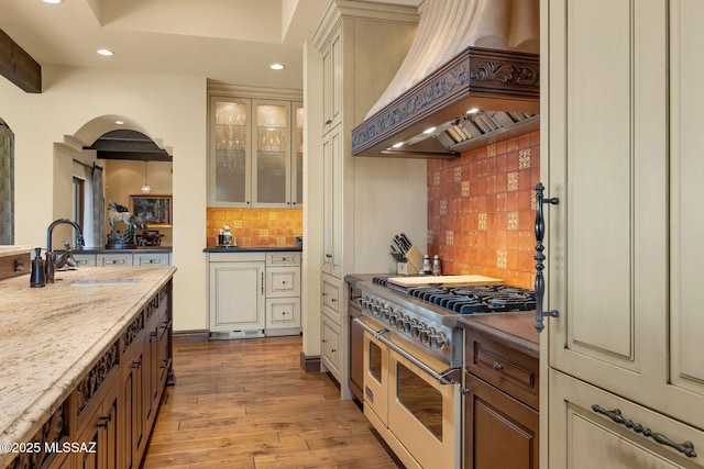 kitchen featuring premium range hood, wood finished floors, double oven range, a sink, and recessed lighting