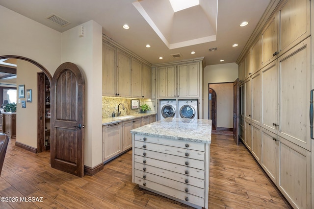 kitchen with arched walkways, washing machine and dryer, hardwood / wood-style flooring, a sink, and dishwasher