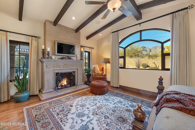 bedroom with wood finished floors, multiple windows, vaulted ceiling with beams, and a premium fireplace