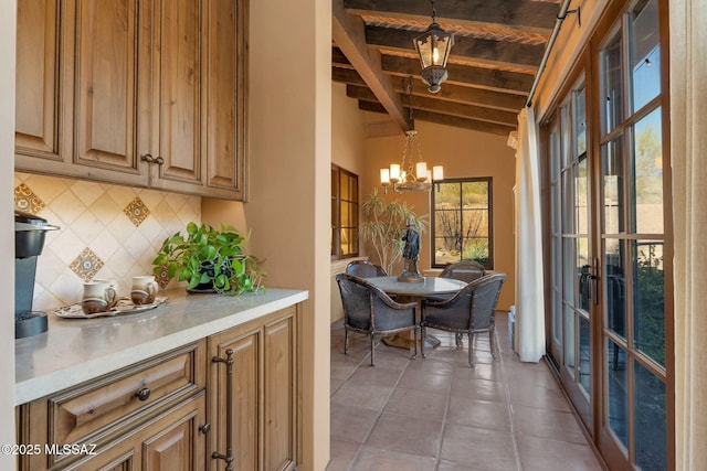 interior space featuring tile patterned floors, vaulted ceiling with beams, hanging light fixtures, a chandelier, and backsplash