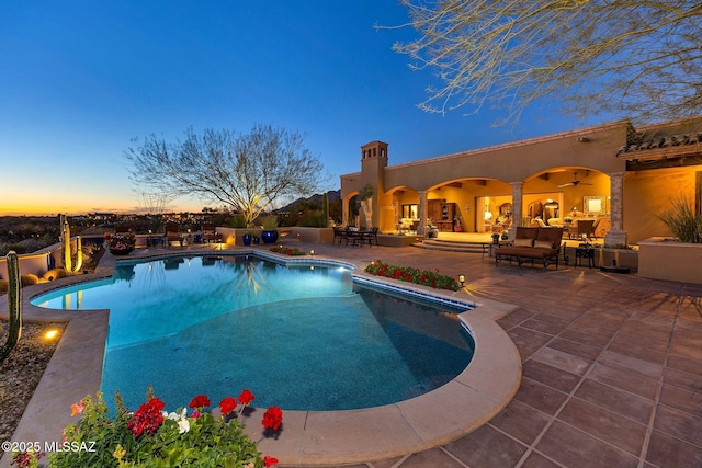 pool at dusk featuring an outdoor hangout area, a patio area, and a fenced in pool