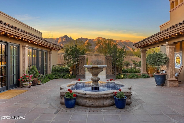 patio terrace at dusk featuring fence and a mountain view