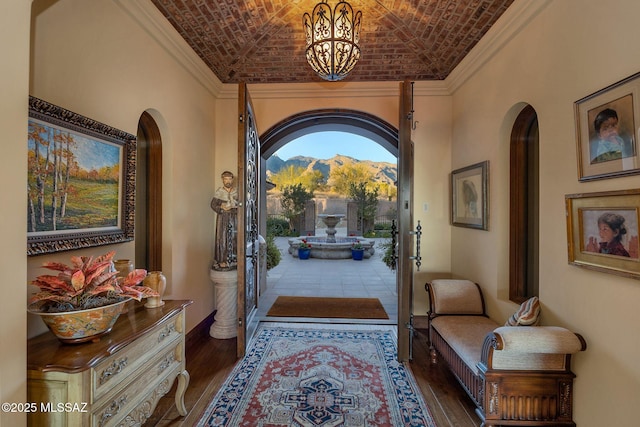 foyer with brick ceiling, hardwood / wood-style floors, arched walkways, and a mountain view