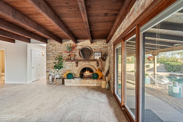 interior space featuring wood ceiling, an outdoor brick fireplace, baseboards, and beamed ceiling