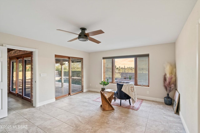 office space with light tile patterned floors, a ceiling fan, a wealth of natural light, and baseboards