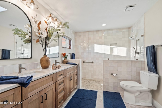 bathroom featuring toilet, tile walls, visible vents, and a sink