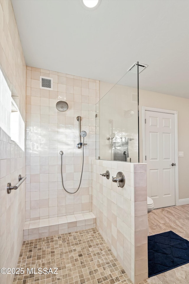 bathroom with toilet, visible vents, and a tile shower