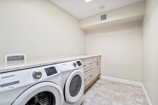 clothes washing area with cabinet space, baseboards, visible vents, and separate washer and dryer