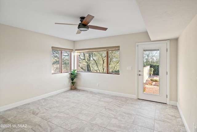 spare room featuring a healthy amount of sunlight, baseboards, and a ceiling fan