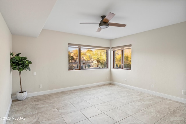 empty room with a ceiling fan and baseboards