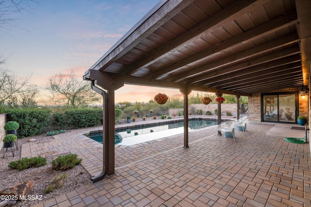 patio terrace at dusk featuring a fenced in pool and fence