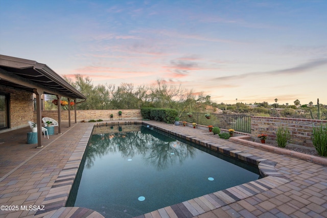 pool at dusk featuring a patio area, a fenced backyard, and a fenced in pool