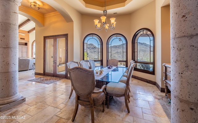 dining area featuring a chandelier, baseboards, a towering ceiling, and stone tile flooring