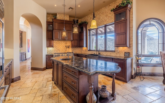 kitchen featuring a sink, visible vents, baseboards, and stone tile flooring