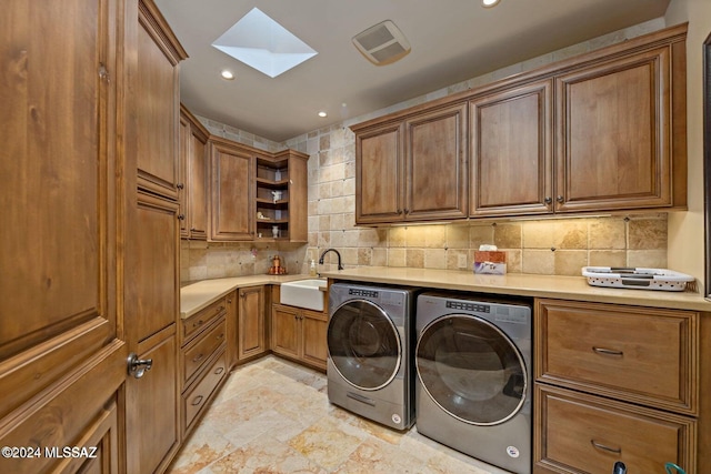 washroom with visible vents, washer and dryer, a skylight, cabinet space, and a sink