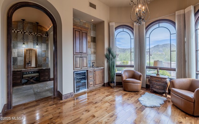 sitting room with a bar, light wood-style floors, beverage cooler, and visible vents