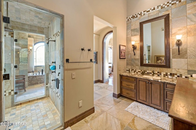 full bathroom with tiled shower, vanity, and baseboards