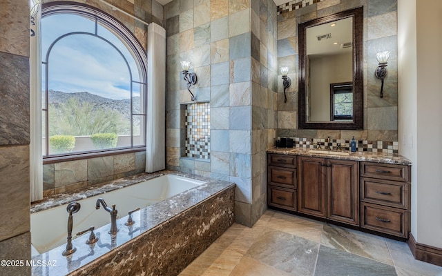 full bath with visible vents, a garden tub, a mountain view, tile walls, and vanity