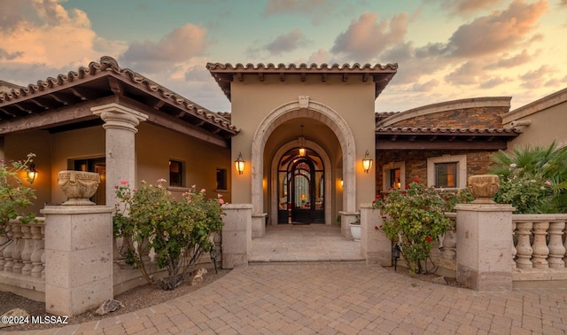 doorway to property with french doors, a tile roof, and stucco siding