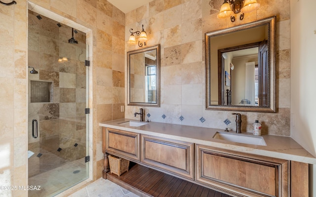 bathroom featuring decorative backsplash, double vanity, a stall shower, and a sink