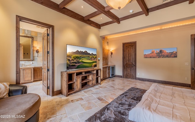 bedroom featuring stone tile floors, beam ceiling, and baseboards