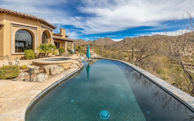 outdoor pool with a mountain view and an in ground hot tub